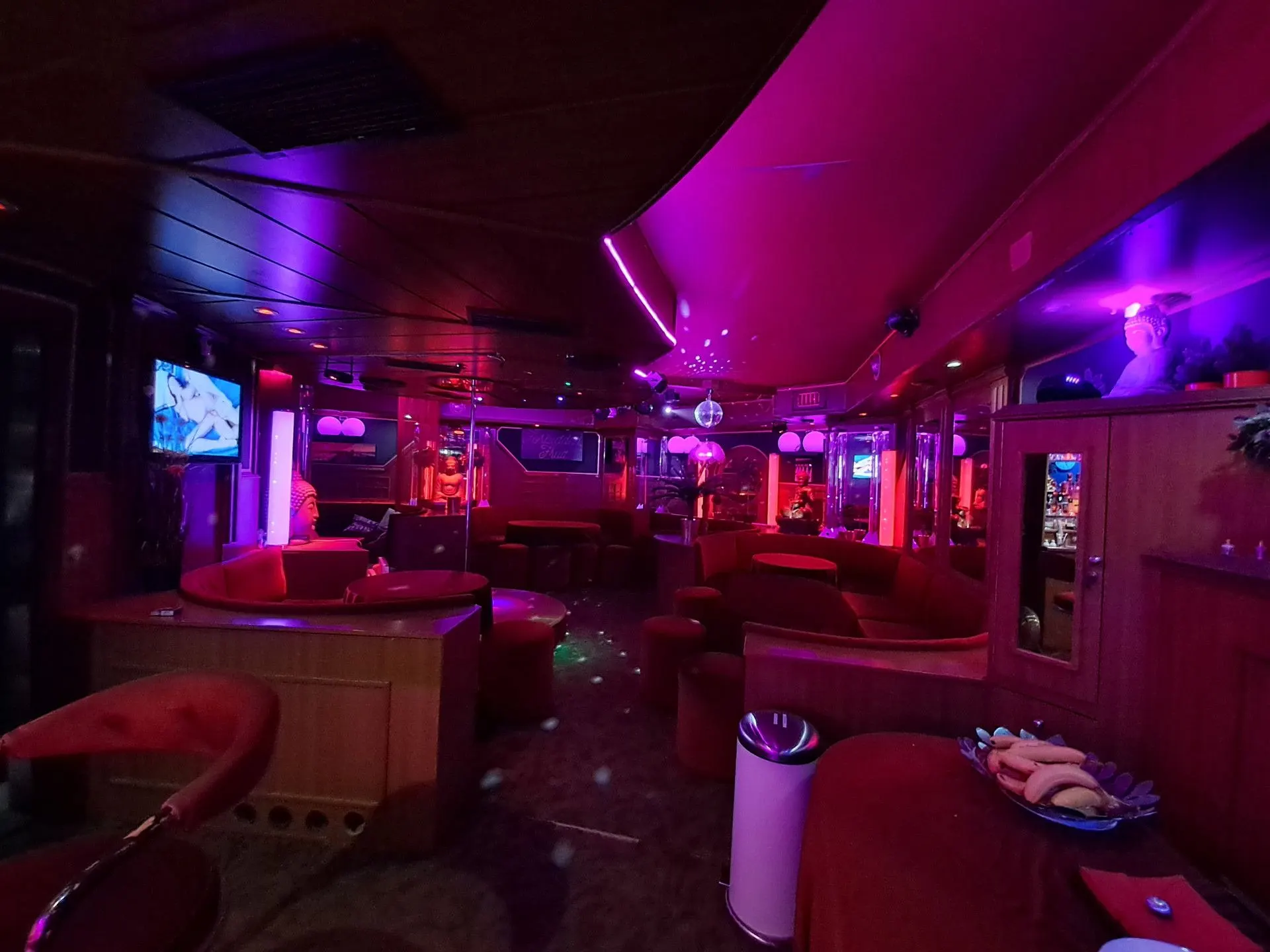 Lounge with red sofas and a TV screen in purple mood lighting