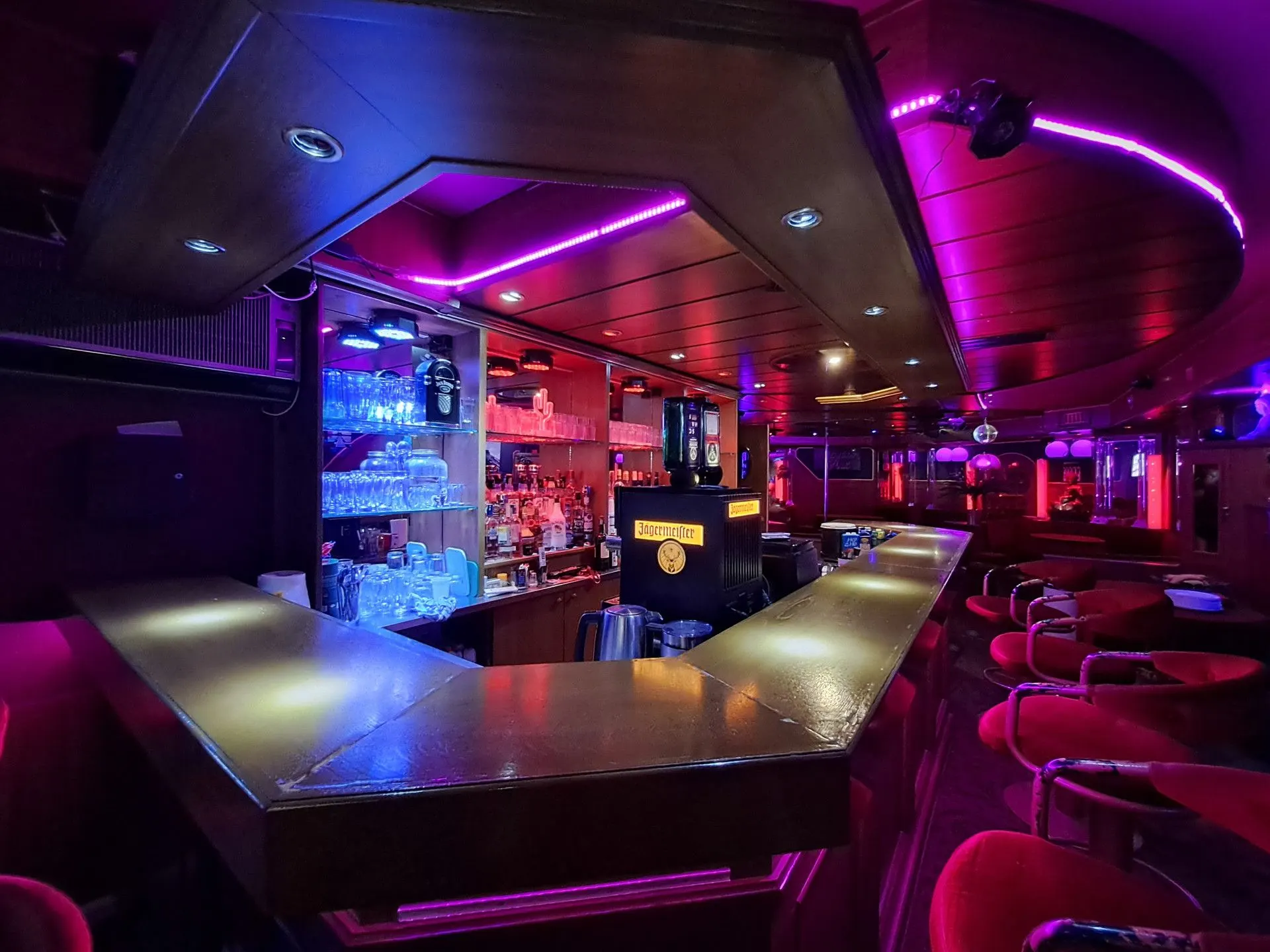 Bar counter with backlit glass shelves in purple light