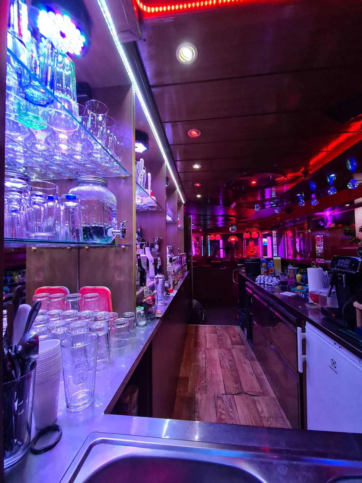 Glass shelves behind the bar with a red light strip and worktop