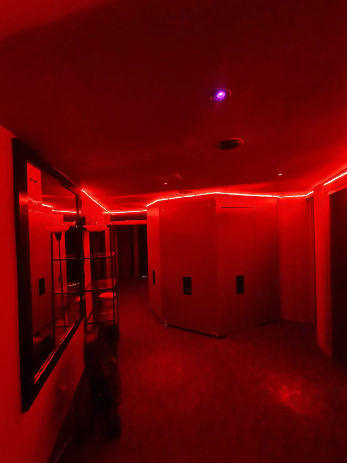 Section of corridor bathed in red light with an LED strip on the ceiling