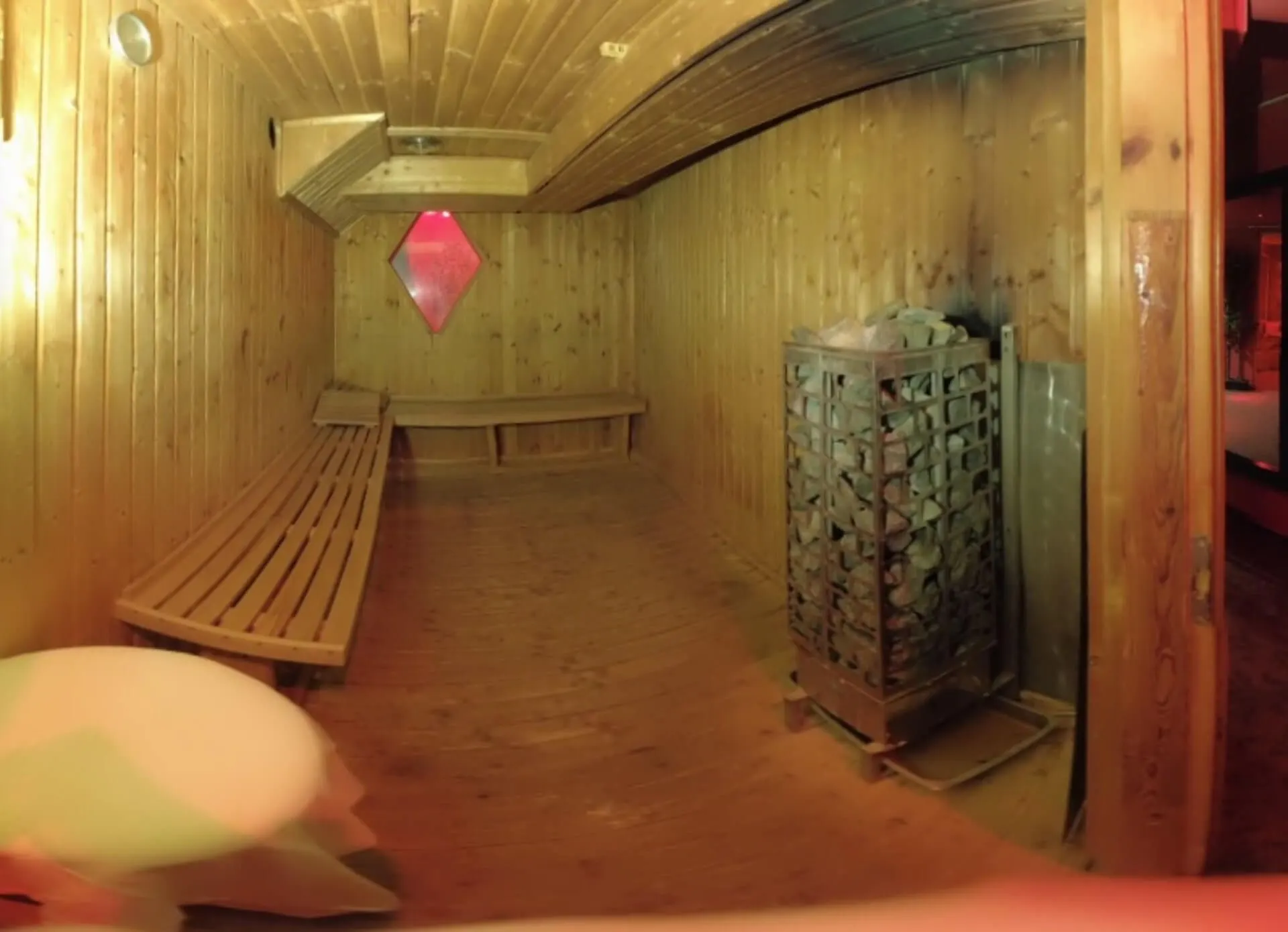 Sauna interior with wooden benches and a rock-filled heater