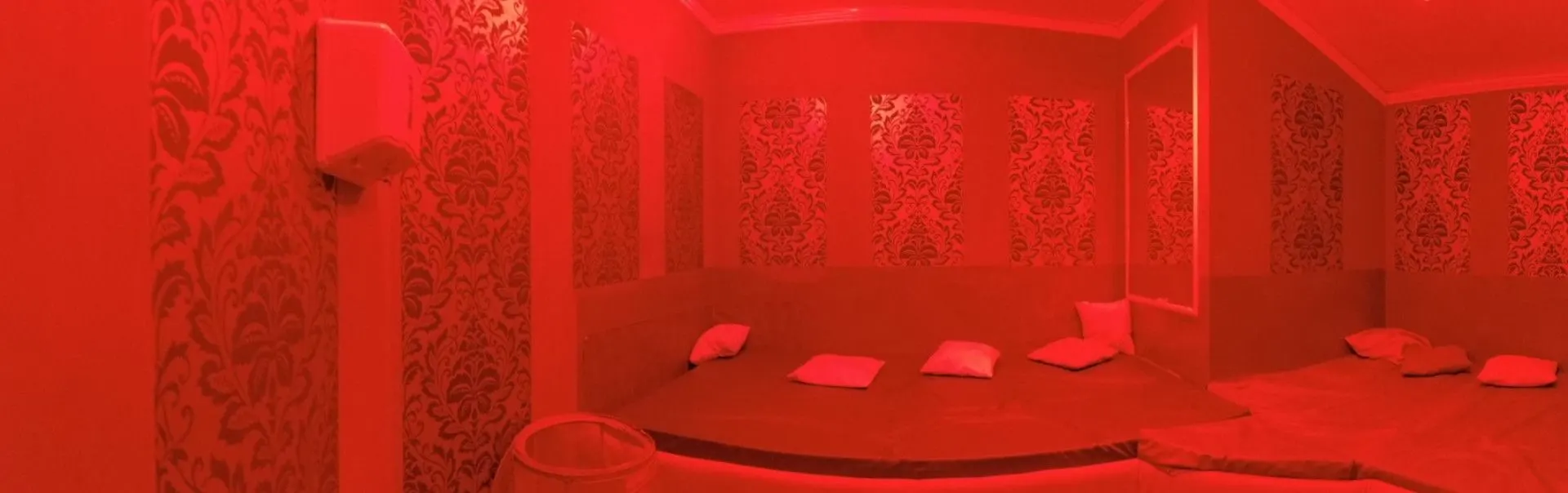 Red-lit playroom with a large round bed and cushions