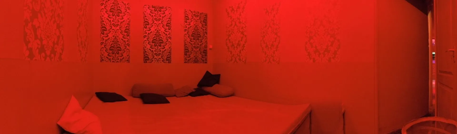 Bed with dark pillows in a red-lit room
