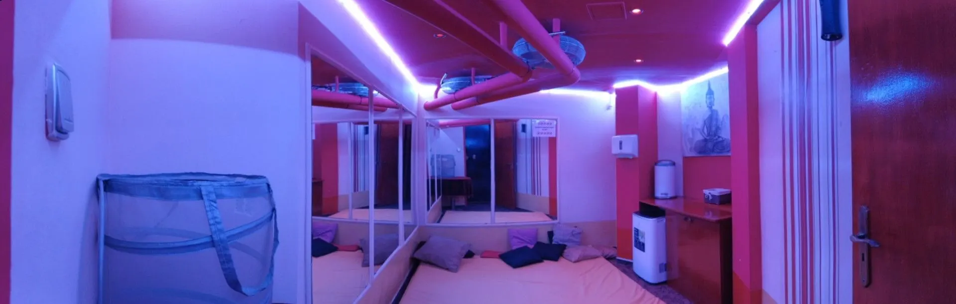 Mirrored room with a purple LED strip and a low bed