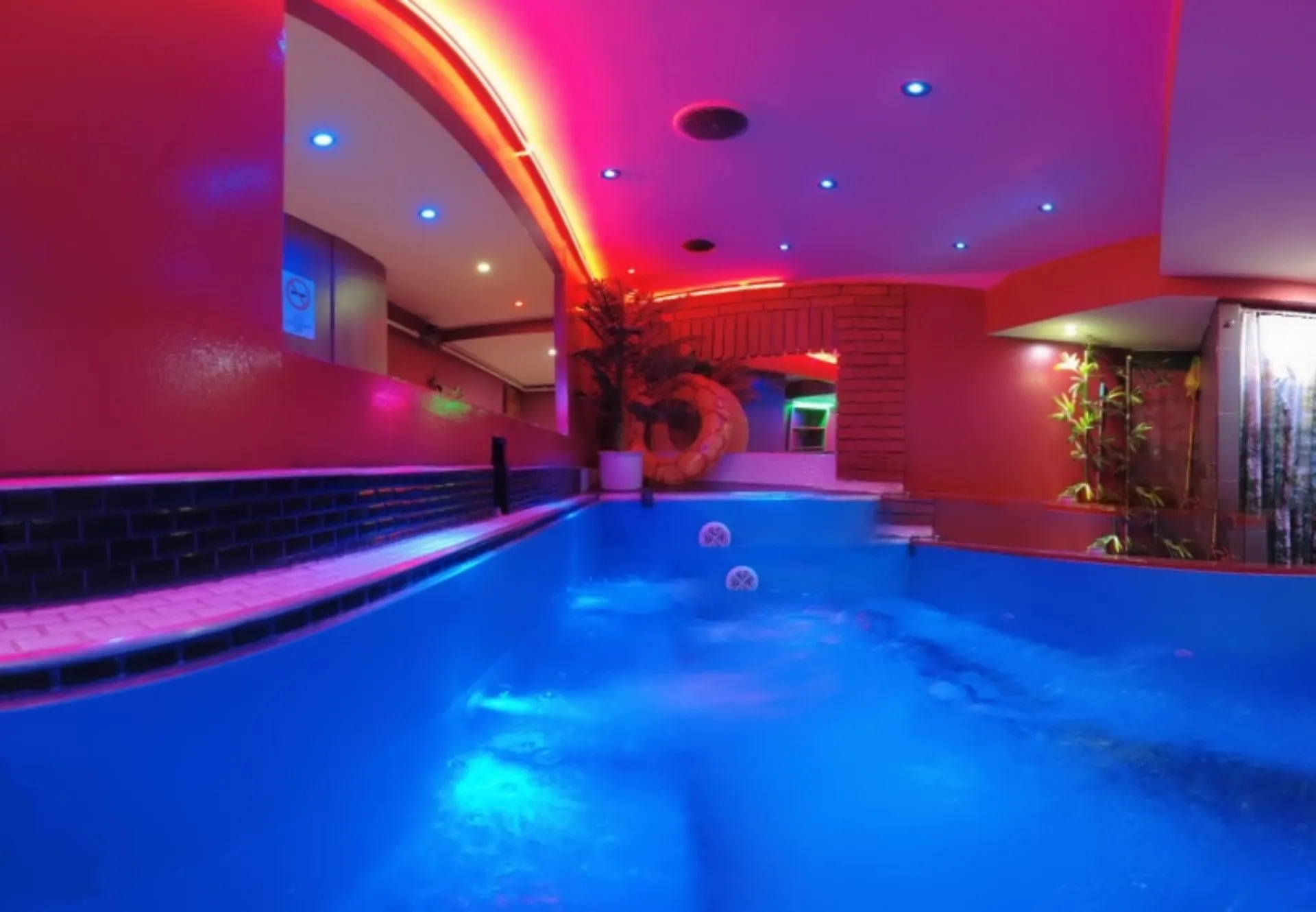 Bubbling jacuzzi in blue light under a red neon ceiling