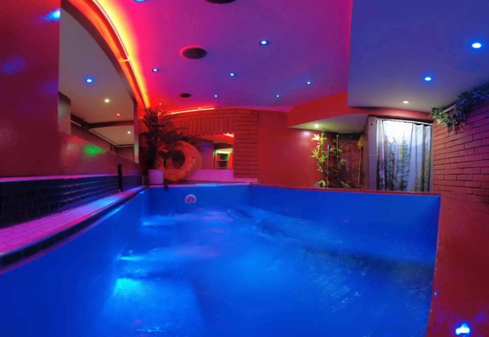 Jakuzzi kék vízzel, téglafallal és függönnyel a háttérben