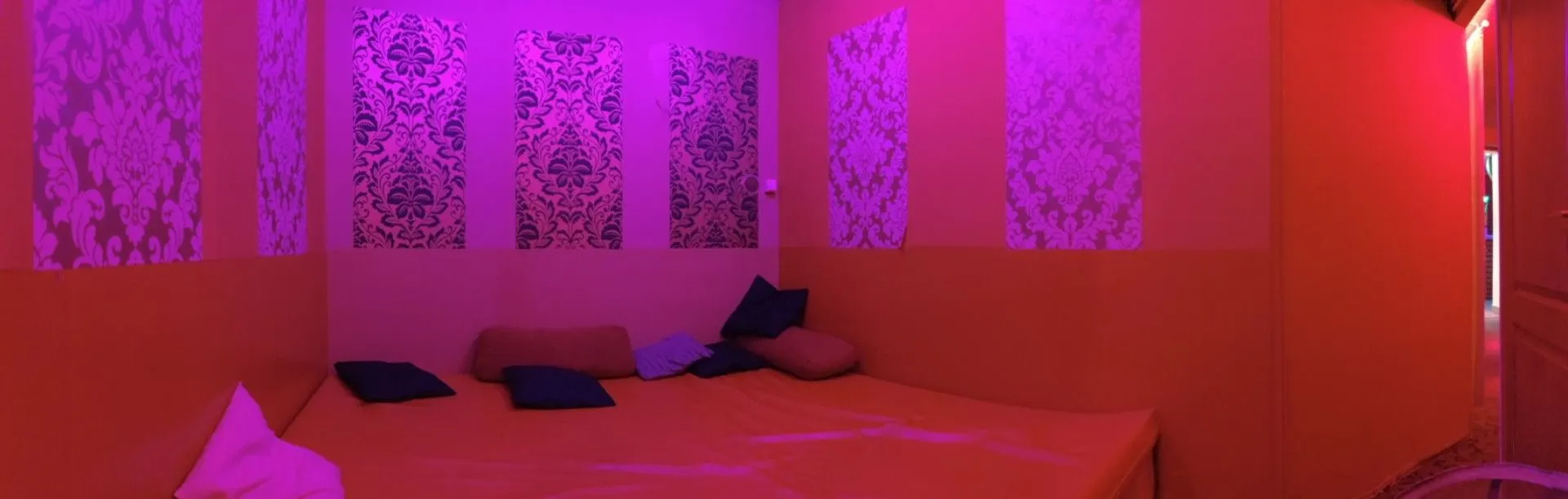 Bed against a patterned wallpaper wall in magenta light