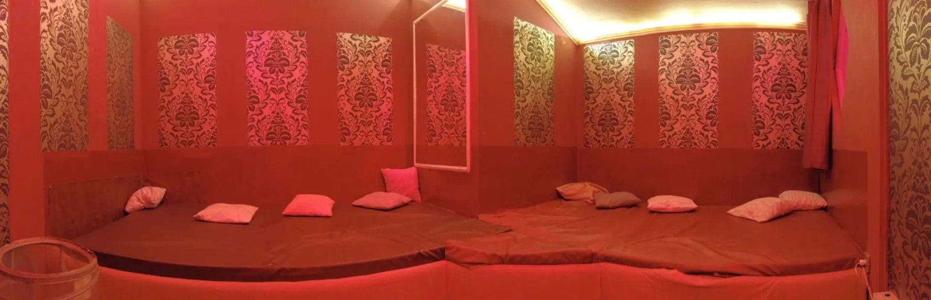 Wide bed with cushions in a room with patterned wallpaper