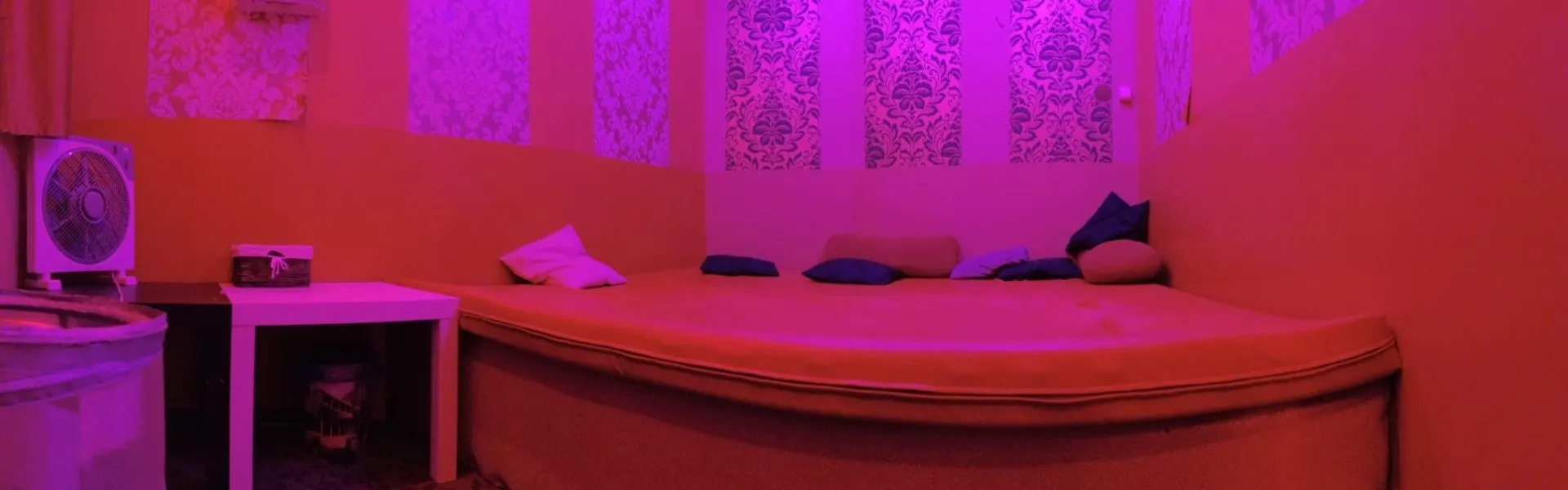 Round bed in a purple-lit room