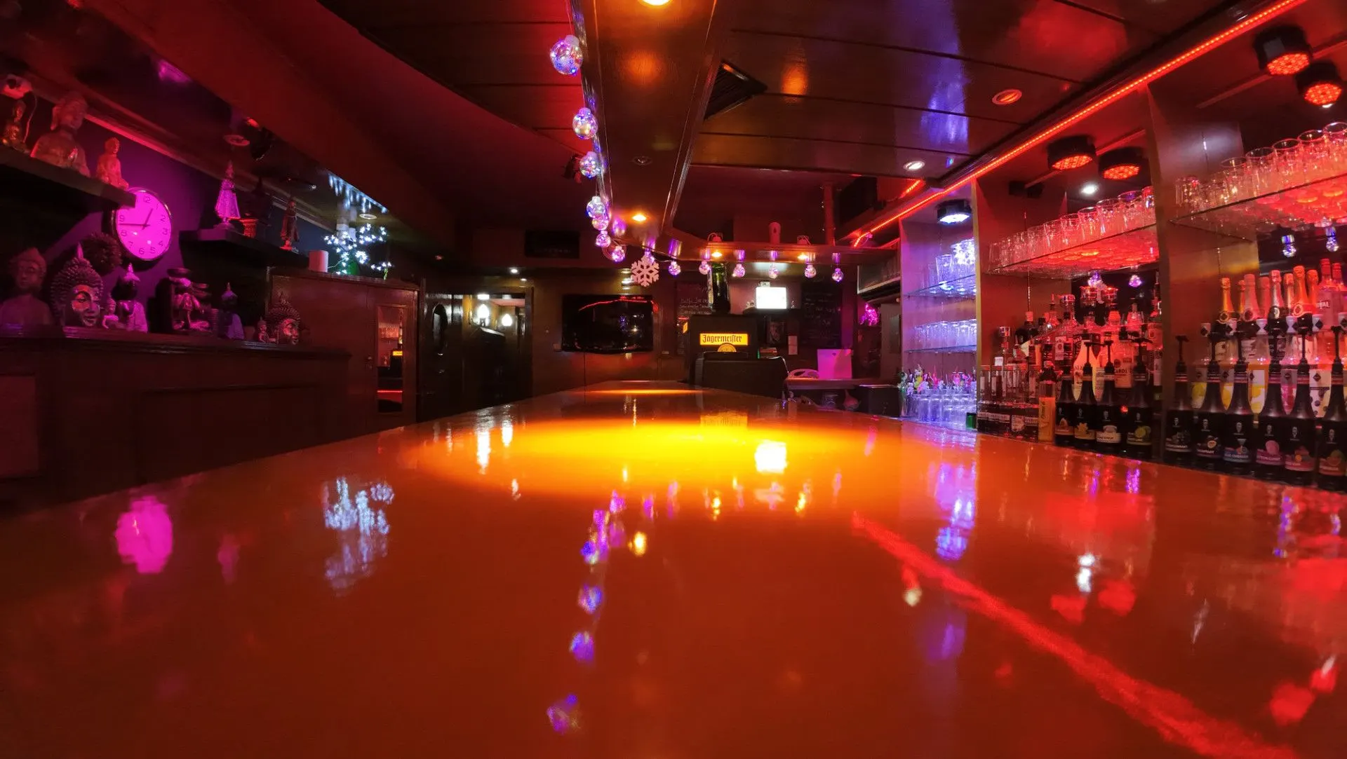 Glossy bar counter reflecting pink and orange lights