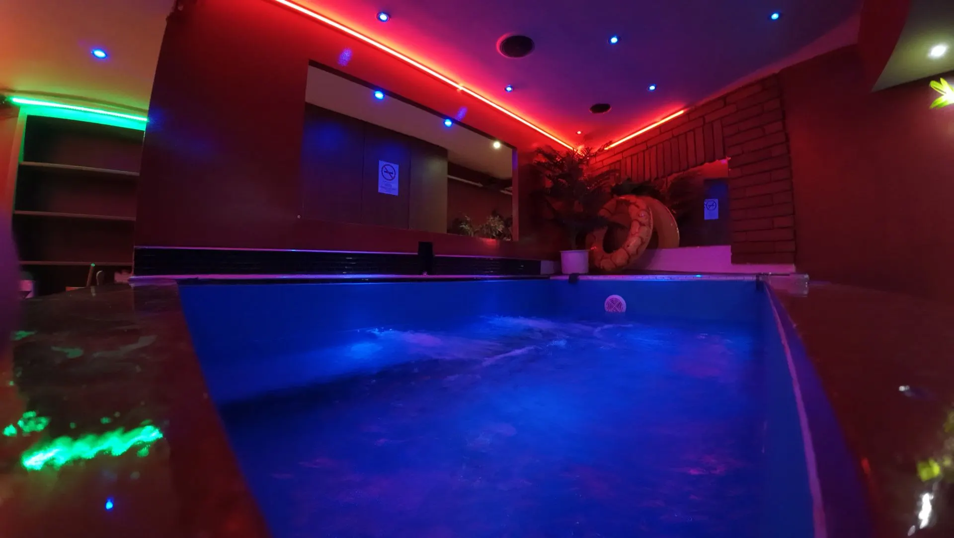 Corner of the jacuzzi with a red neon ceiling and green light